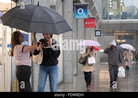 Gli acquirenti ottenere catturati in una pesante pioggia su London Victoria Street. Foto Stock