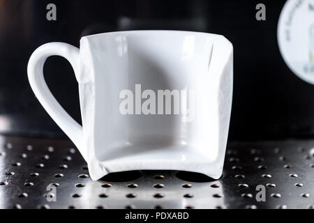 Close up su bianco tazza di caffè rotto in metà posto sulla home macchina espresso. Concetto di bad mattina Foto Stock