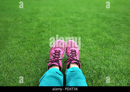 Piedi in scarpe da tennis in erba verde. Sullo sfondo della natura Foto Stock