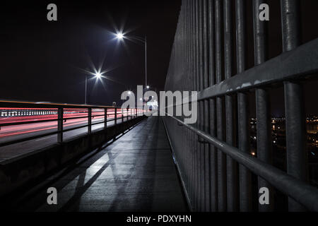 La seconda Narrows Bridge marciapiede di notte, con sentieri di luce dai veicoli in transito. Foto Stock