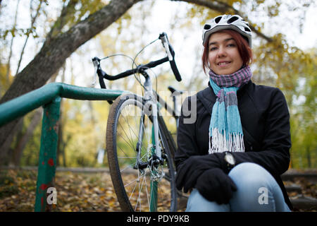 Immagine della donna seduta sulle scale accanto alla bicicletta Foto Stock