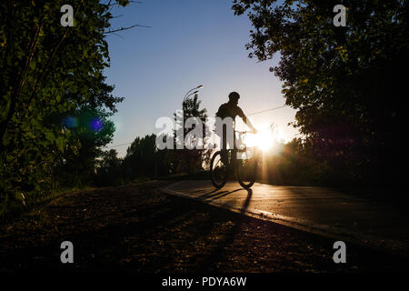 Immagine del ciclista che indossa il casco equitazione intorno città in serata Foto Stock