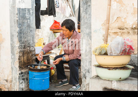 Hongcun Village, Cina - 18 ottobre 2014. Donna vendita di verdure, carni e spezie, visualizzata al di fuori di un piccolo negozio. Sapori locali ed esotiche fo Foto Stock