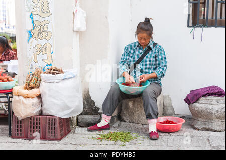 Hongcun Village, Cina - 18 ottobre 2014. Donna vendita di verdure, carni e spezie, visualizzata al di fuori di un piccolo negozio. Sapori locali ed esotiche fo Foto Stock