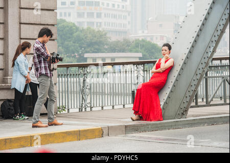 Shanghai, Cina - 20 ottobre 2014. Fotografo e una moda femminile modello durante un servizio fotografico su un ponte sopra il fiume Huangpu a Shanghai. Foto Stock