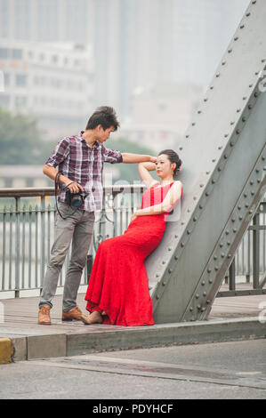 Shanghai, Cina - 20 ottobre 2014. Fotografo e una moda femminile modello durante un servizio fotografico su un ponte sopra il fiume Huangpu a Shanghai. Foto Stock