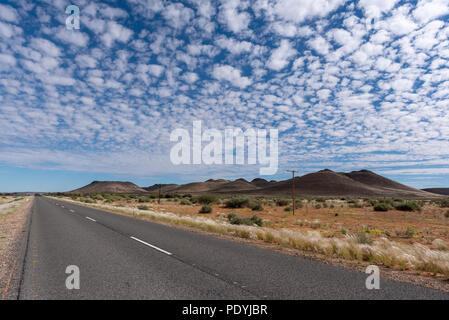 Strada diritta che conduce all'orizzonte e bellissime sparse bianche nuvole nel cielo blu Foto Stock