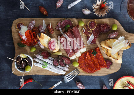 Tipiche tapas spagnole concetto. includono diverse fette di prosciutto, il chorizo, salame, bocce con olive e peperoni. Copyspace. Foto Stock