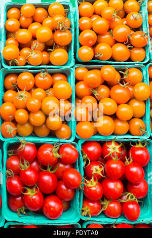 Cartoni di arancione e rosso varietà di ciliegia matura i pomodori sul display Foto Stock