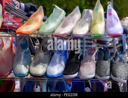 In gomma e silicone, sandali e scarpe da ginnastica sulla calzatura ripiano nel mercato. Foto Stock