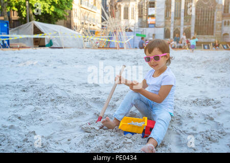 Poco ragazza seduta nel sandbox e giocare con stampi sul parco giochi Foto Stock