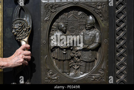 Una donna si apre il bronzo massiccio porte di ingresso presso la Cattedrale Basilica di San Francesco di Assisi a Santa Fe, New Mexico. Foto Stock