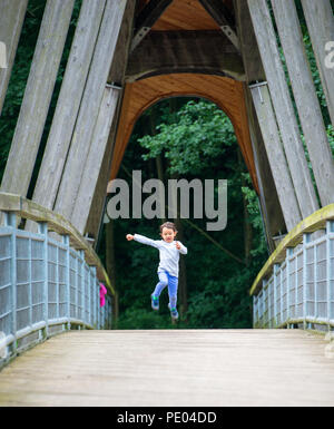 Bambino divertirsi da correre e saltare Foto Stock