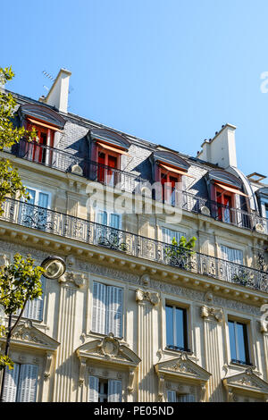 Vista dal basso la strada di un tipico parigino, opulento-cercando di edificio in stile haussmanniano con taglio facciata in pietra, ornamenti intagliati e balcone. Foto Stock