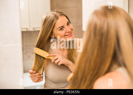 Bella donna pettinare i capelli nel bagno. Foto Stock