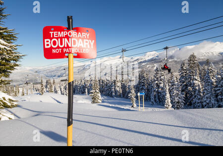 Le tracce nella neve accanto a una ski area segno di confine. Foto Stock