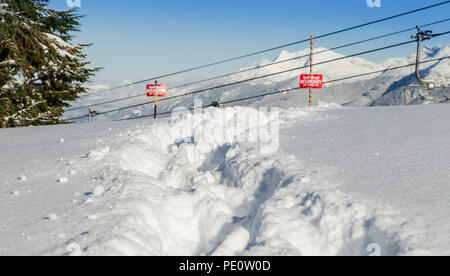 Le tracce nella neve accanto a una ski area segno di confine. Foto Stock