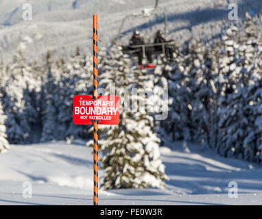 Le tracce nella neve accanto a una ski area segno di confine. Foto Stock