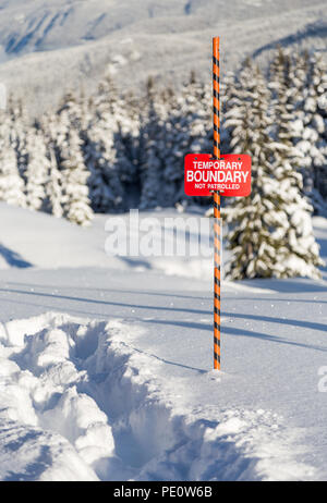 Le tracce nella neve accanto a una ski area segno di confine. Foto Stock