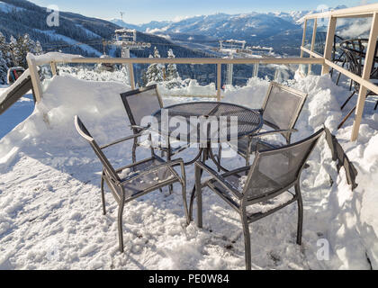 Sedie su una coperta di neve con il ponte di una seggiovia torre in background. Foto Stock