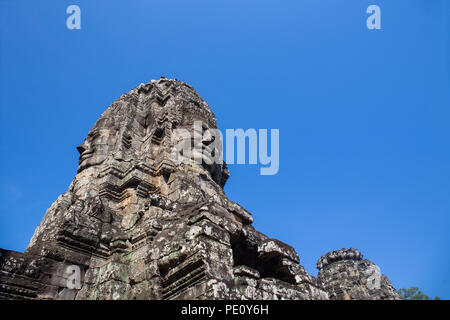 Serena e sorridente facce di pietra torre di Jayavarman VII sul cielo blu di Prasat tempio Bayon in Angkor Thom, Siem Reap , Cambogia Foto Stock