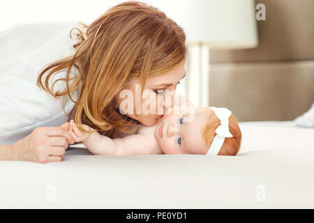 Una nonna felice kissing baby nipote sul letto. Foto Stock