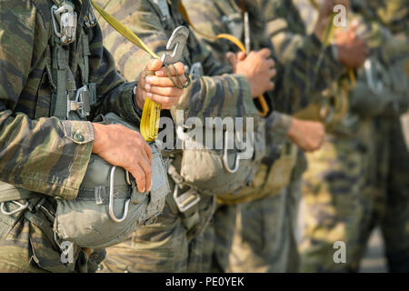 Fila di polizia paracadutista in uniforme di mimetizzazione tenere premuto T-10 static line gancio e paracadute di riserva nel tono di qualità cinematografica con spazio di copia Foto Stock