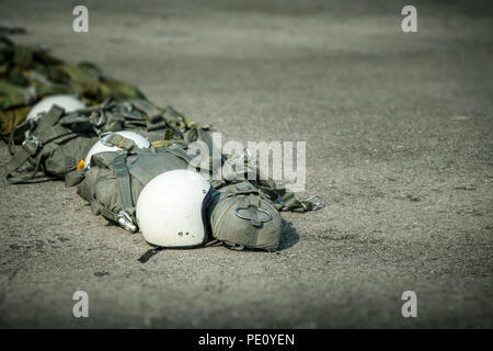 Fila di T-10 paracadute tattico borsa con paracadute di riserva e casco a terra a prepararsi per paracadutista al funzionamento con spazio di copia Foto Stock