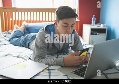 Uomo che utilizza il telefono cellulare con il computer portatile Foto Stock