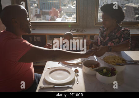 Famiglia pregare prima di avere la prima colazione sul tavolo da pranzo Foto Stock