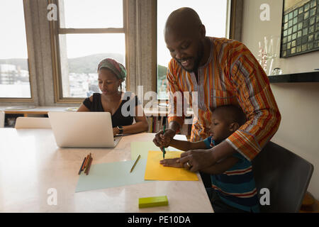 Padre che assiste il suo figlio per disegnare una bozza Foto Stock