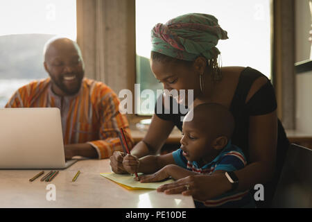 Madre che assiste il suo figlio per disegnare una bozza Foto Stock