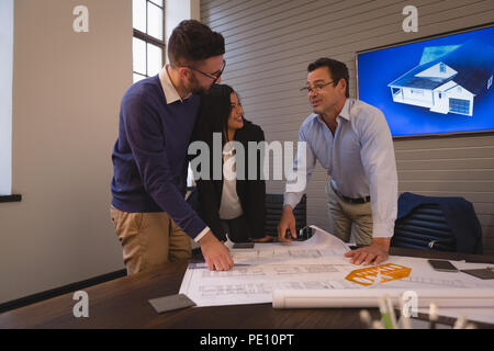 Colleghi di lavoro discutendo su blueprint in sala riunioni Foto Stock