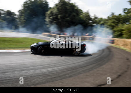 Un convertibile Jaguar sportscar gira i suoi pneumatici, creazione di fumo, su una pista a Goodwood Festival of Speed 2018. Foto Stock