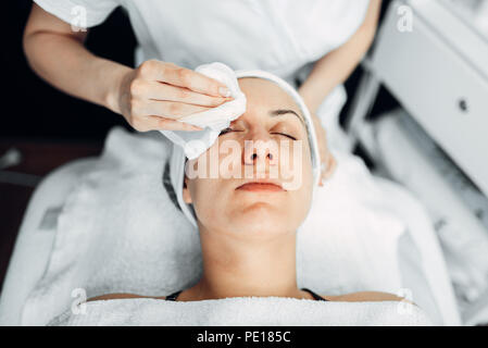 Estetista mani sfrega la crema sul paziente femmina faccia vista superiore, la cosmetologia clinica. Cura della pelle del viso, procedura di ringiovanimento nella spa salone Foto Stock