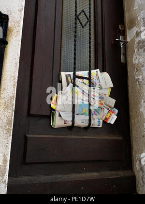 La posta indesiderata a sinistra si incunea nella porta di una casa in Cessenon-sur-Orb, Francia Foto Stock
