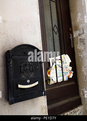 La posta indesiderata a sinistra si incunea nella porta di una casa in Cessenon-sur-Orb, Francia Foto Stock