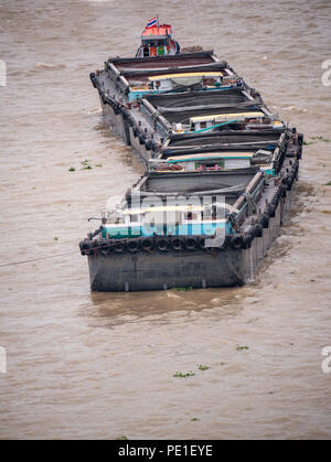 Una chiatta, un fondo piatto nave,per trasportare la sabbia nel fiume Chaopraya trascinare dal rimorchiatore a traino, ad alto angolo di vista, Bangkok, Thailandia Foto Stock