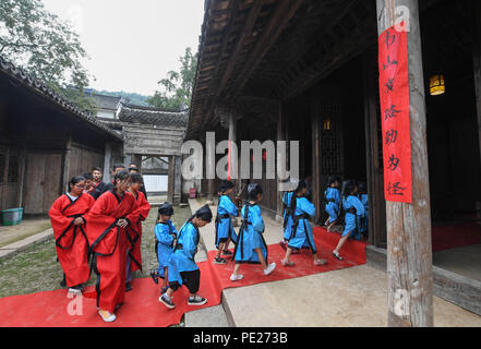 Changxing cinese della provincia dello Zhejiang. 12 Ago, 2018. Gli studenti a piedi in un vecchio stile a scuola privata di sperimentare una classe tradizionale nel villaggio di Zhongshan nella contea di Changxing, est della Cina di Provincia dello Zhejiang, Agosto 12, 2018. Credito: Xu Yu/Xinhua/Alamy Live News Foto Stock