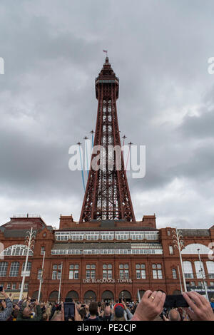 Blackpool, Regno Unito. 12 Agosto 2018 - RAF frecce rosse sorvolare la Blackpool Tower alla fine della annuale airshow di Blackpool. Le frecce rosse ha volato per lo sfondo di un emergente tempesta, ed eseguita per una folla di decine di migliaia di lungo la passeggiata di Blackpool. Credito: Benjamin Wareing/Alamy Live News Foto Stock