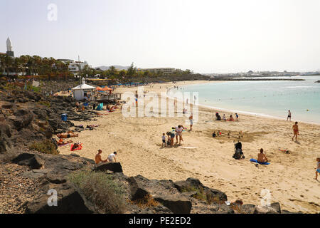 LANZAROTE, Spagna - 18 Aprile 2018: la splendida vista di Playa Dorada Beach con i bagnanti sulla sabbia, Lanzarote, Isole Canarie Foto Stock