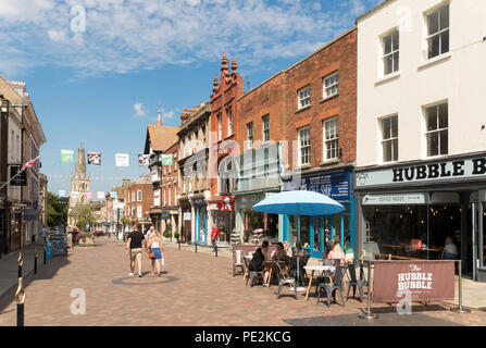 Paio di camminare e di persone al di fuori seduta cafe, centro città, Westgate St, Gloucester, England, Regno Unito Foto Stock