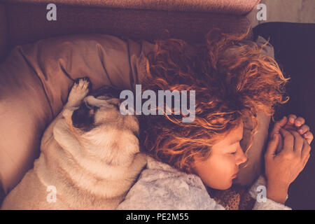 I concetti di amicizia per 40s donna che dorme con i suoi migliori amici pug cane a casa. Entrambi sul cuscino e marrone e i toni caldi. Sognare insieme. Amore e Foto Stock