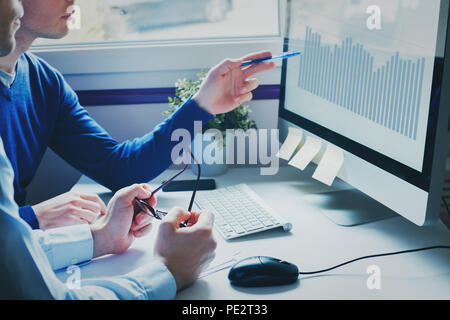 Un gruppo di giovani uomini di affari che colleghi cercando insieme al computer, il team di lavoro sul nuovo progetto di avvio in un ufficio moderno, il concetto di brainstorming Foto Stock