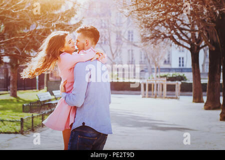 Dating, giovani caucasici felice coppia baciare e ridere insieme all'esterno Foto Stock