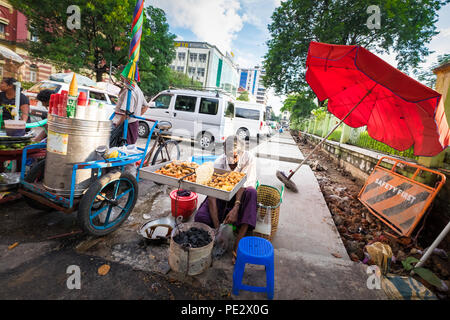 Un uomo vendita di una selezione di fritti snack di Yangon Foto Stock