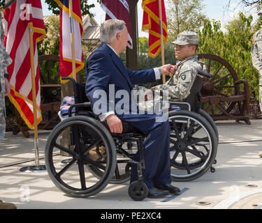 Texas Gov. Greg Abbott awards il Texas cuore viola a Spc. Jose Romo nel corso di una cerimonia svoltasi a Fort Sam Houston a San Antonio, Sett. 24, 2015. Romo e altri tre Texas guardie nazionali sono state distribuite con il primo squadrone, 112reggimento di cavalleria, che è stato parte della forza multinazionale e osservatori (MFO) missione in Egitto, quando essi hanno ricevuto le loro ferite. (U.S. Esercito nazionale Guard foto di Sgt. 1. Classe Malcolm McClendon) Foto Stock