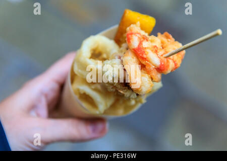 Cibo di strada italiano a Venezia - fritto misto (misto di pesce fritto, calamari o calamari e gamberi) in un cono in movimento Foto Stock