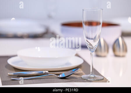 Impostazione tabella in una moderna sala da pranzo con un tavolo bianco e posate, stile scandinavo Foto Stock