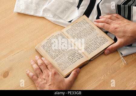 Uomo ebraico mani un libro di preghiere, pregando accanto al tallit. Jewish simboli tradizionali. Rosh hashanah (ebreo nuovo anno di vacanza), Shabbat e Yom Foto Stock